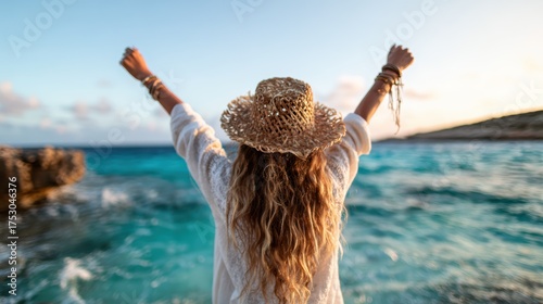 A cheerful woman stands with outstretched arms at the beach, enjoying the refreshing sea breeze and the beauty of the ocean during sunset, symbolizing freedom and joy.