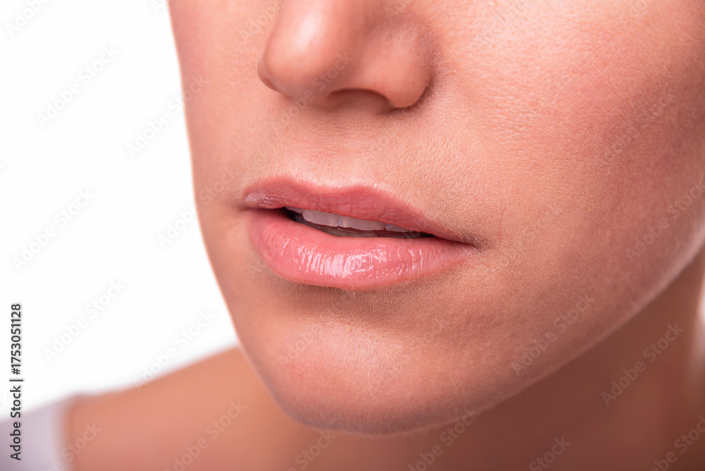 Obraz premium A woman's mouth and lower face, emphasizing natural lips and skin texture, is presented on a white background.