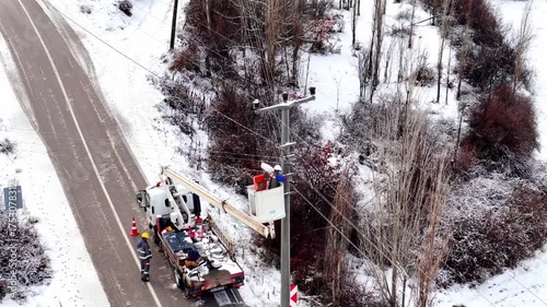 Workers repairing power lines on a snowy day, ensuring energy flow despite harsh winter conditions.