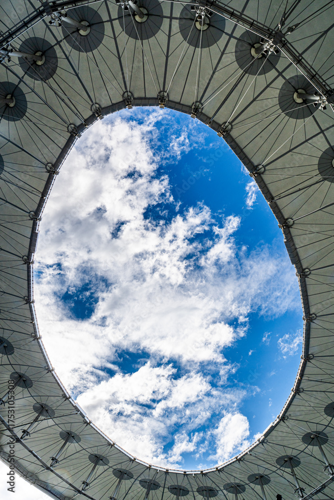 Fototapeta premium Fragment of a modern building, roof with a hole in the sky with clouds