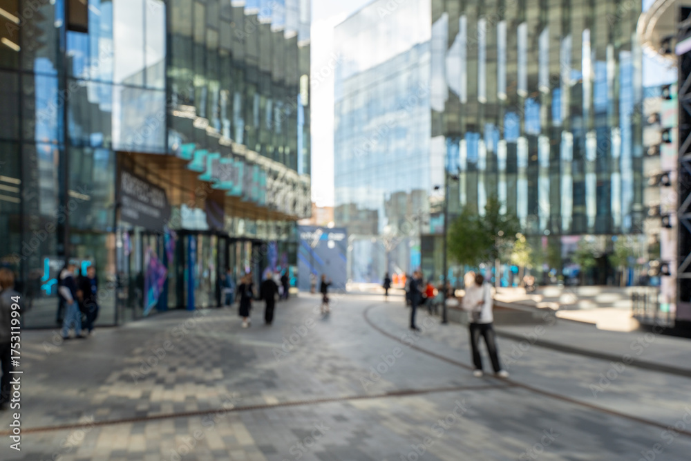 Fototapeta premium Blurred photo: a business center in a metropolis, modern office buildings with passing people. High quality photo