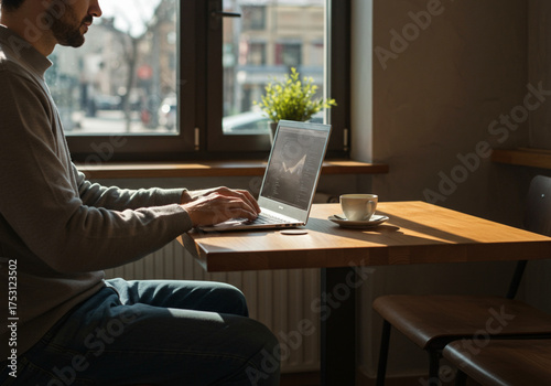 Young professional in a cafe, intently analyzing a financial growth chart on his laptop while enjoying a cup of coffee