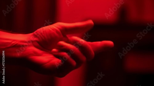 Close up of a human hand gesturing in dramatic red light.
