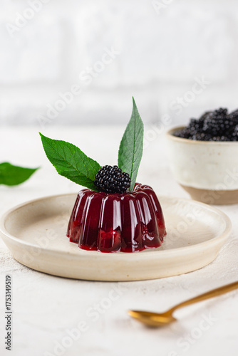 Delicious jelly with cherry, blackberry and green cherry leaves in a light table. Healthy food, sugar, gelatin and lactose free. Vertical orientation.