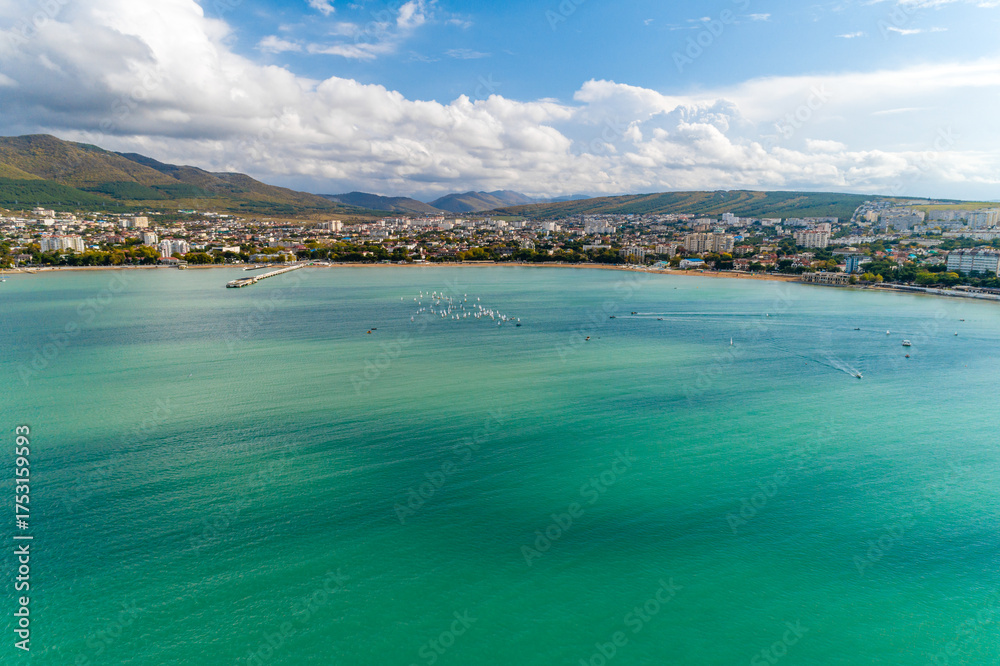 Naklejka premium Yacht competitions in Gelendzhik Bay. Many small yachts on water. Aerial view. Caucasus Mountains in background. Children's regatta
