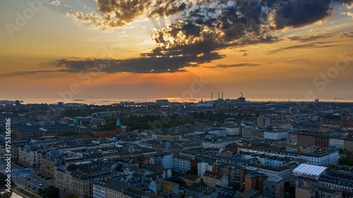 Aerial drone time lapse over Copenhagen rooftops and waterfront with sun rays breaking through the clouds at sunset