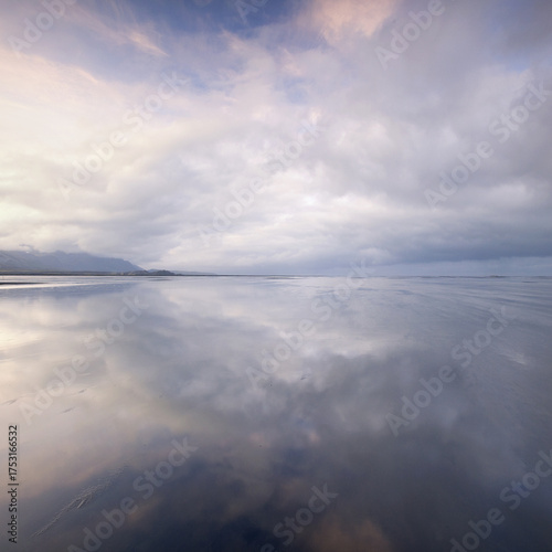 Wallpaper Mural View of the serene landscape with a mirror-like water surface reflecting the dramatic sky above, creating a sense of boundless space, Dyrholaey, Iceland. Torontodigital.ca