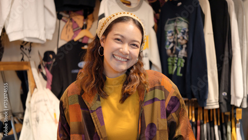 Young teen Gen Z asia female happy smile looking at camera at zero waste eco go green buy second hand sale store flea market mall thrift old used vintage fabric retro style. Woman people enjoy shop.
