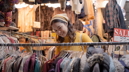 Foto Young teen tourist Gen Z asia female choose look at zero waste eco go green buy second hand sale store flea market thrift old used vintage fabric style
