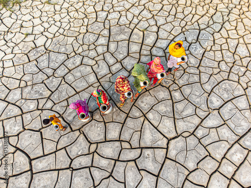 Gabura Union, Bangladesh - 25 April 2025: Aerial view of women walking across parched earth, their vibrant clothing a stark contrast to the cracked, arid landscape.