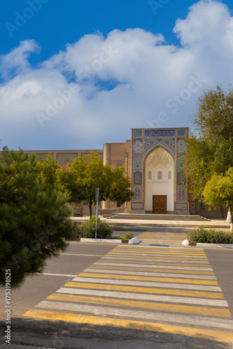 An empty zebra pedestrian crossing across the road in front of the Mir Arab Oliy Madrasah at sunny day in Bukhara, Uzbekistan.