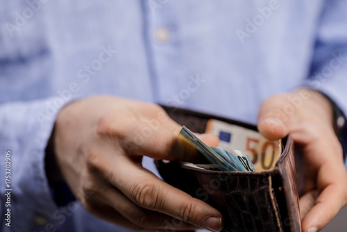 Slika na platnu Close-up shot of a man's hands opening a leather wallet filled with euro banknotes, symbolizing financial concepts and economic activity