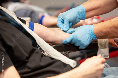 Therapist inserting a needle into a donor vein during blood transfusion procedure