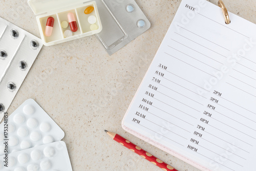 Flat lay composition with pill box, blister packs and medical schedule list on light background, healthcare and pharmaceutical concept showing treatment, prevention and medication organization