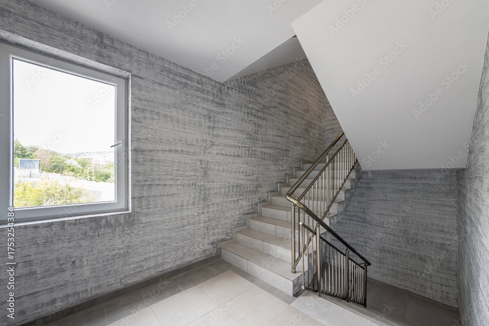 Obraz premium Modern stair case between floors. Stairs with metallic rail in modern building. Interior of a contemporary apartment or office building. Architecture and real estate background.
