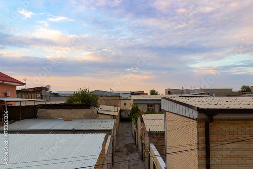 View on flat rooftops of houses under sunset sky in the old quarter with narrow street in Bukhara, Uzbekistan