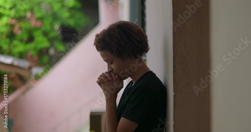 Obraz na plátně One Hispanic young boy of African descent with curly hair, eyes closed, hands cl