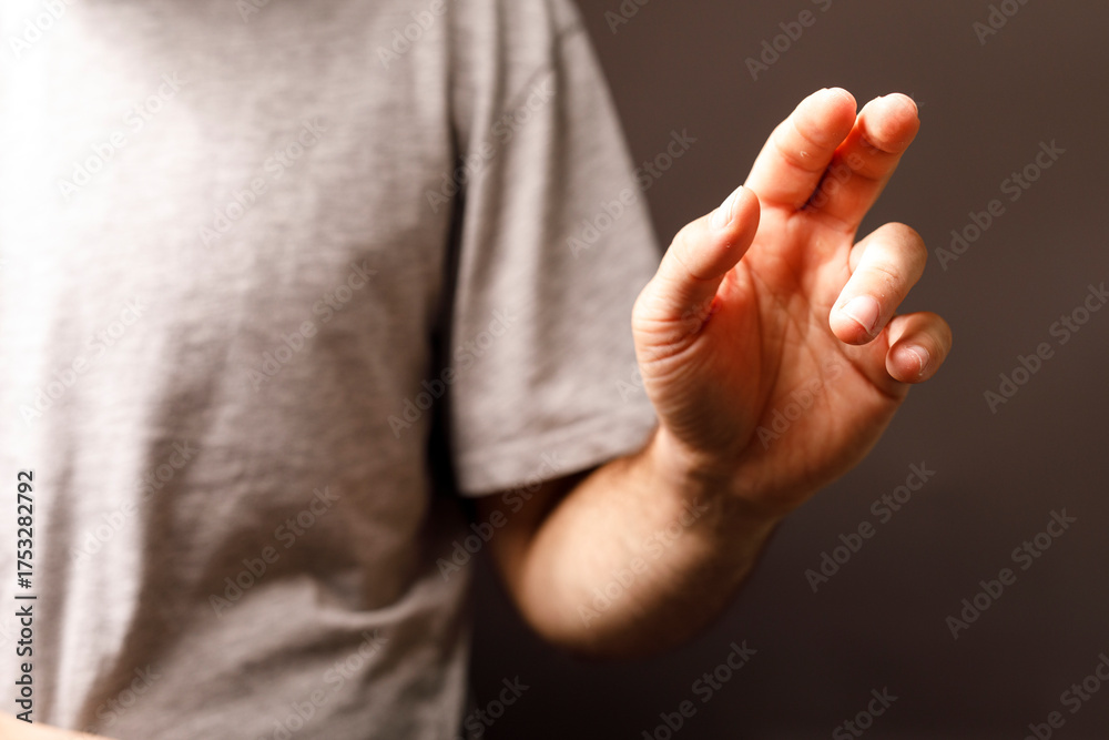 Obraz premium Man's hand gesturing upwards, suggesting direction or offering. The hand is central against a plain background. Focus on fingers and arm.
