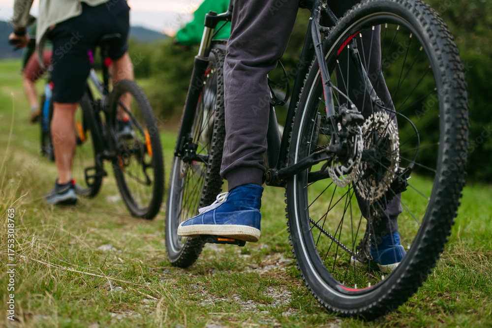 Fototapeta premium Cyclists riding mountain bikes on grassy trail.
