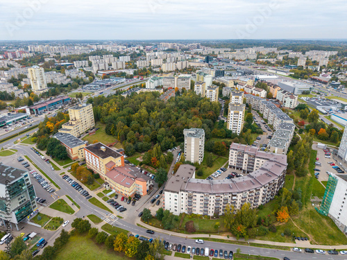 Aerial drone photo of Pašilaičiai district in Vilnius, Lithuania, showing Laisvės Avenue, roundabout, and nearby forest area on an autumn day.