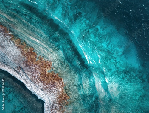 Aerial view of a turquoise ocean meeting a brown reef, with white foamy waves