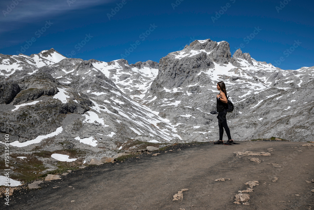 Fototapeta premium Adventurous woman explores stunning snow-capped mountains under vibrant blue sky, perfect for inspiring travel and outdoor lifestyle campaigns, get inspired today