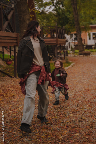 A little girl catches up with her mother on a walk in the autumn courtyard.