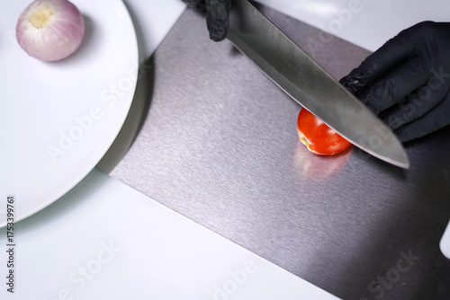 Close-up of cutting tomato on kitchen chopping board.