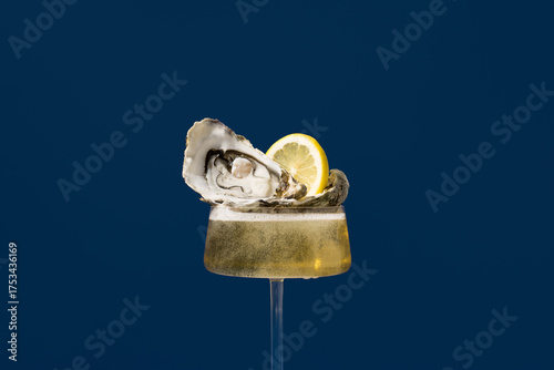 Champagne glass with oyster and lemon on blue