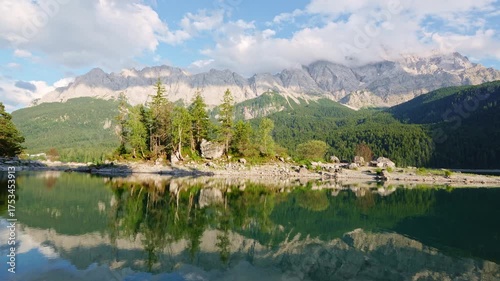 Eibsee Lake, Mountain Slopes with Forest, Island and Zugspitze Massif on Sunny Day. Ripple and Reflection on Water. Bavaria, Germany