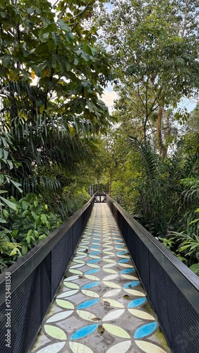 bridge in the park. A vibrant, patterned walkway extends through lush green jungle foliage, leading towards a distant wooden bridge bathed in soft light.