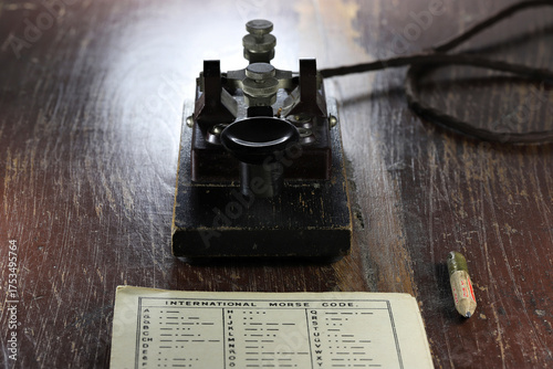 morse key with morse code chart on desk