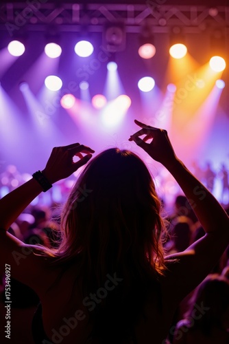 a woman with her hands up in front of a crowd at a concert