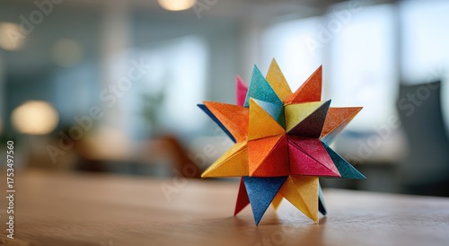 A brightly colored geometric star sculpture sits atop a wooden table in an office setting