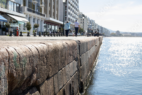 thessaloniki waterfront's stone quay, bathed in mediterranean sun, overlooking the sparkling thermaic gulf. historical city life by the sea