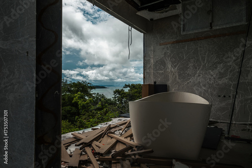 A room in an abandoned hotel. A white bathtub on the floor. A view of palm trees from the abandoned hotel. Shabby walls.	

