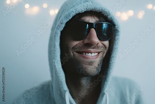 Smirking in shadowy allure, a Caucasian man in a hoodie and shades exudes mystery amid Diwali's twinkling luminance
