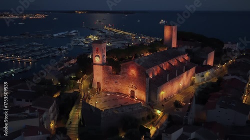 Aerial drone view of Cannes Old Port and the medieval Suquet quarter, with yachts docked in the marina and the Church of Our Lady of Esperance beautifully illuminated