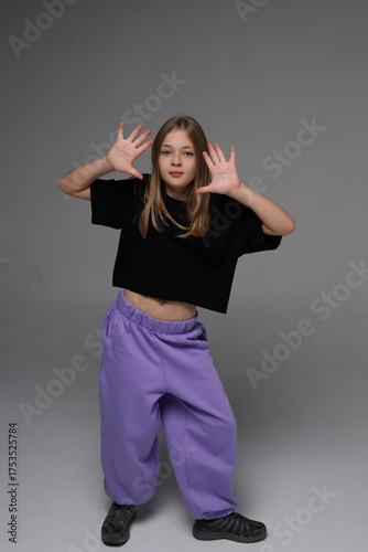 Young caucasian teen girl posing playfully in black top and purple pants