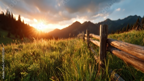 A picturesque sunset casts golden light over rolling hills, with a rustic wooden fence framing the scene, embodying tranquility and beauty in nature’s canvas.