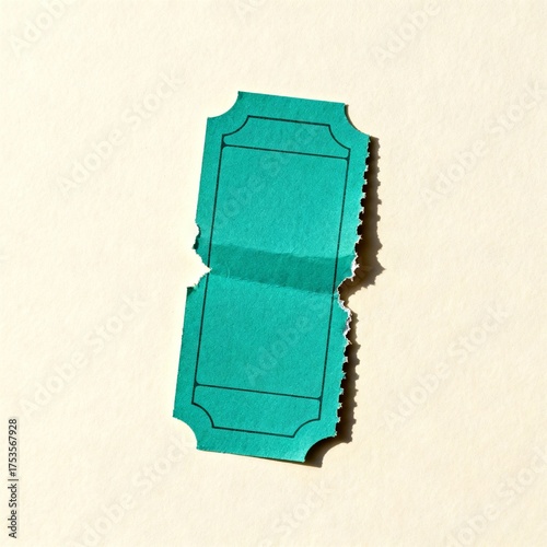 Teal torn movie ticket stub folded in half on beige background, concept of retro design and collectible cinema ephemera