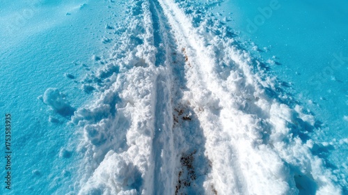 Capturing a snow-covered path leading into the distance, this image evokes feelings of winter wonder, adventure, and serenity under a bright blue sky in a tranquil setting.