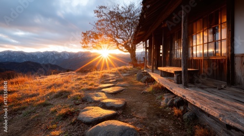 This stunning image captures a serene mountain sunset, featuring warm hues illuminating the sky over a picturesque landscape with rustic wooden structures.