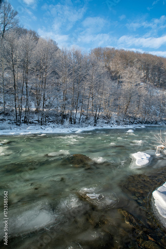 Winter river landscape with frosted trees and clear blue sky during daylight