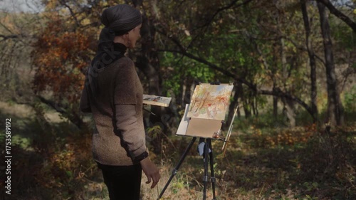 The artist paints an autumn landscape in a park on a sunny day in watercolor