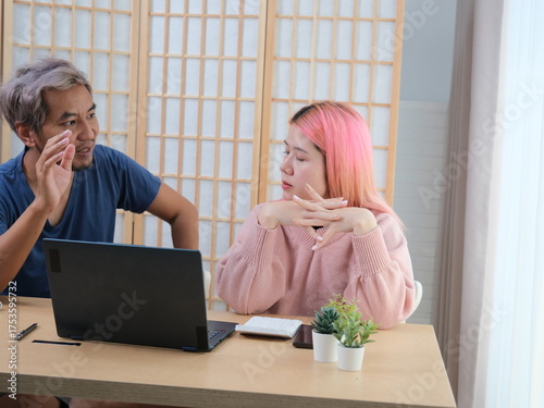 A woman with pink hair is typing on a laptop