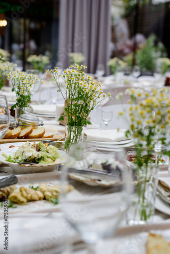 An elegantly decorated banquet table with delicious food and fresh chamomile centerpieces.
