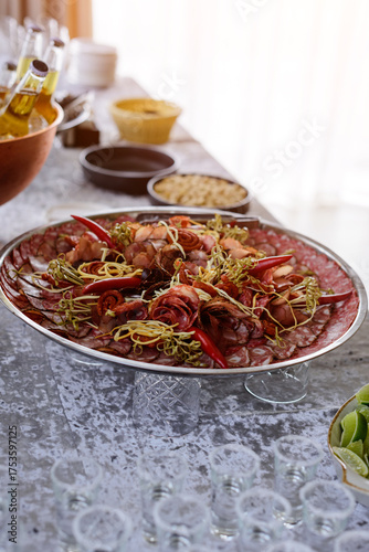 An impressive charcuterie platter featuring a variety of cured meats and spicy red peppers, elegantly served as an appetizer at a catered party or event