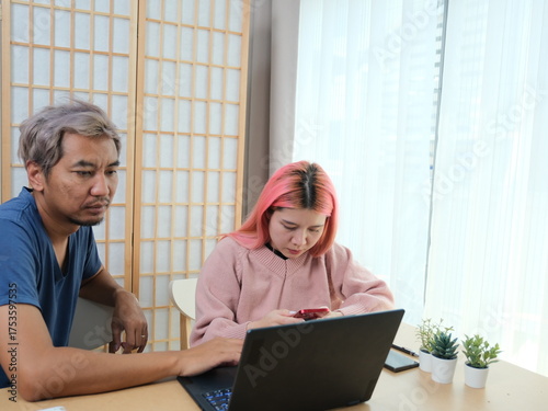 A woman with pink hair is typing on a laptop