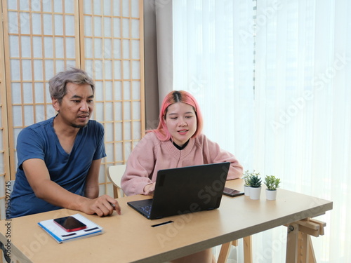 A woman with pink hair is typing on a laptop